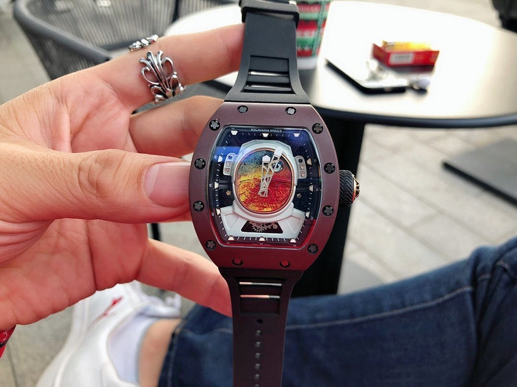 Richard Mille wristwatch held in hand, burgundy case and black strap with openwork dial