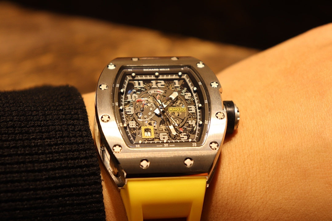 Richard Mille wristwatch with yellow rubber strap and black dial, close front view.