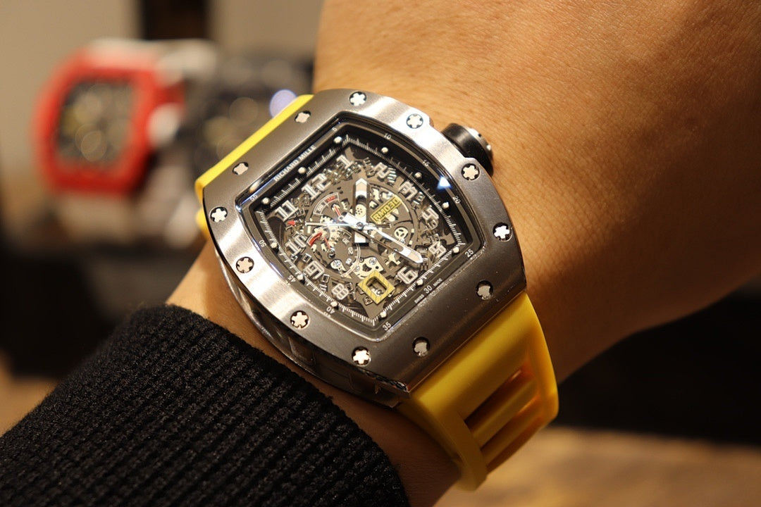 Richard Mille wristwatch on wrist with yellow rubber band and black skeleton dial.