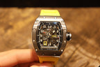 Richard Mille wristwatch held up: yellow strap and black dial with visible subdials.