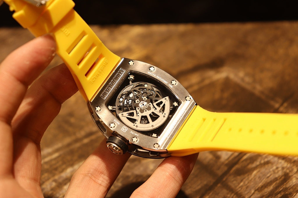 Richard Mille wristwatch side view: yellow strap with black caseback and silver screws.