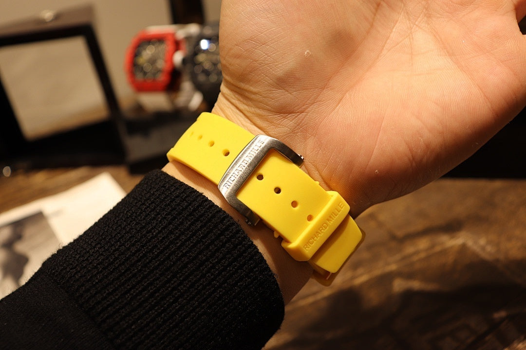 Richard Mille wristwatch band close-up on wrist: yellow rubber strap with buckle area.