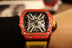 Red skeleton tourbillon watch with yellow strap, exposed mechanical dial