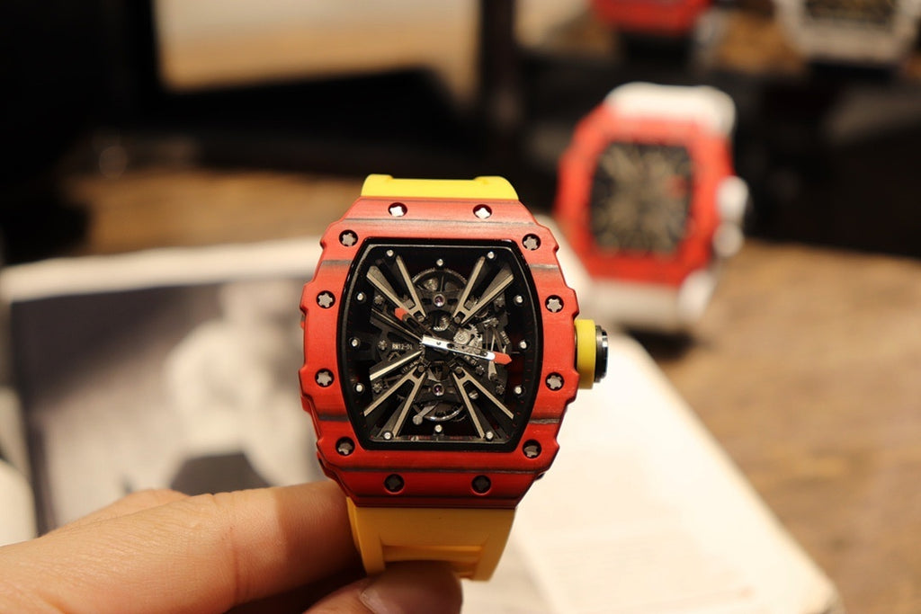 Red skeleton tourbillon watch held in hand with black dial and yellow strap