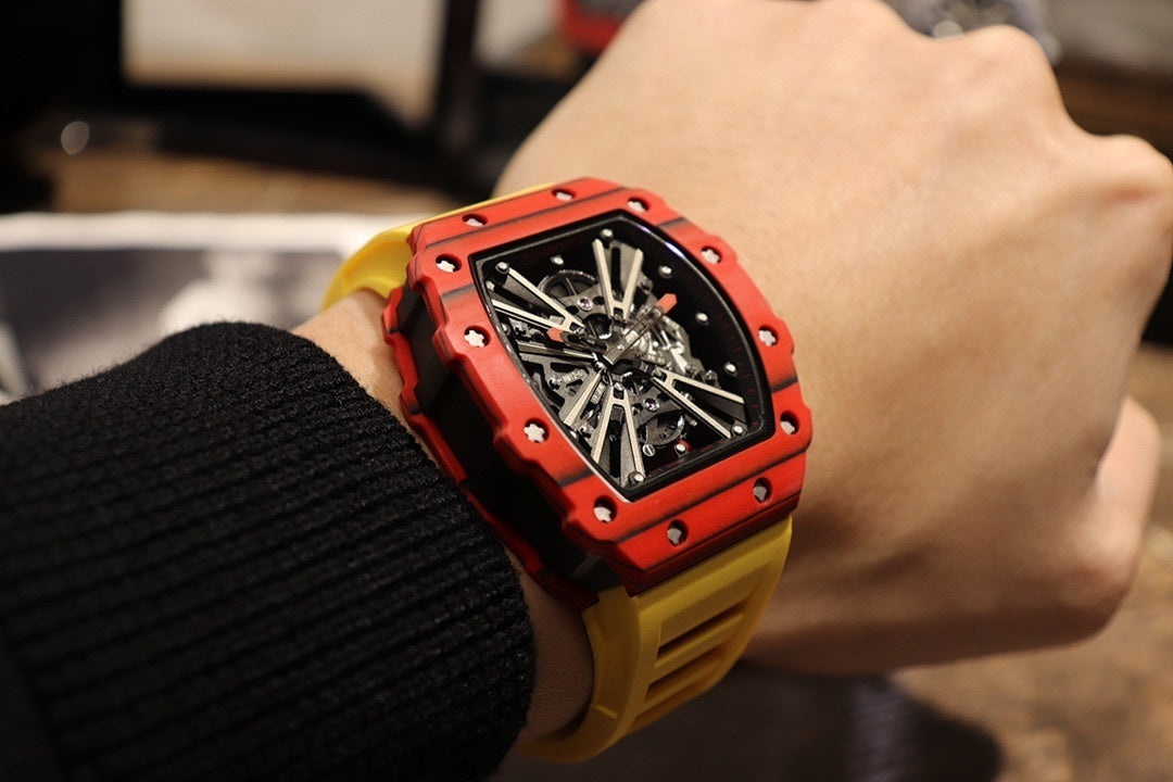 Red skeleton tourbillon watch on wrist with black dial and yellow rubber strap