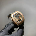Richard Mille watch with gold-toned case, black strap, and open skeleton dial with gears