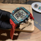 Richard Mille watch top view showing skeleton dial, teal case, red rubber strap.