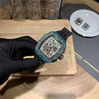 Richard Mille wristwatch on hand, teal bezel, black dial, and black rubber strap