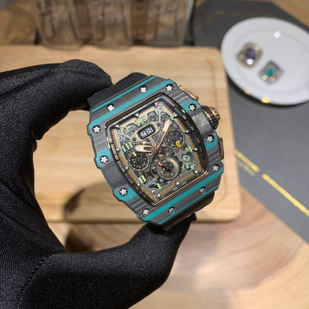 Richard Mille wristwatch close-up with teal bezel, black dial, and black rubber strap