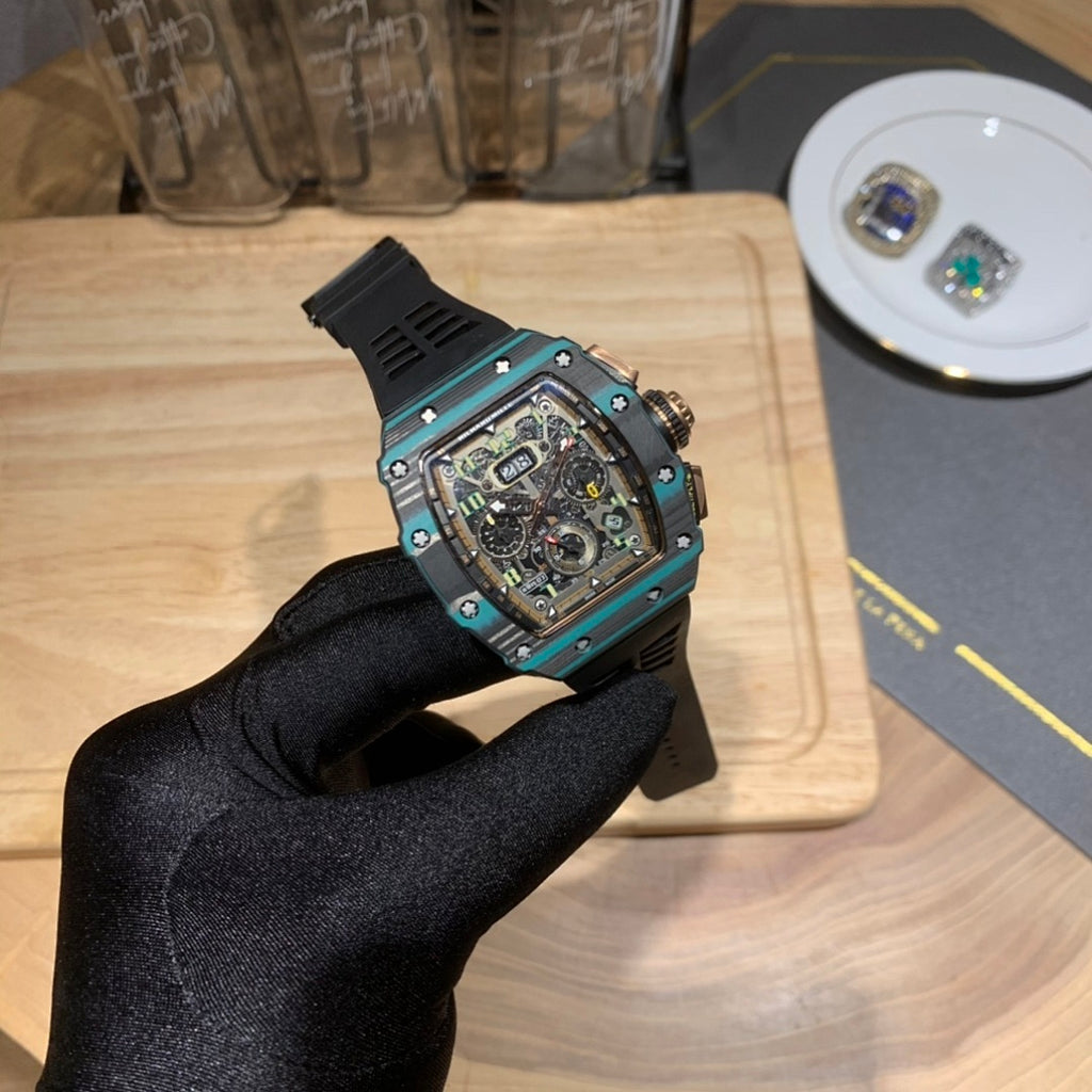 Richard Mille wristwatch angled view with teal bezel, black dial, and black rubber strap