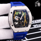Richard Mille watch with blue rubber strap, stainless case, skeleton dial with green accents.