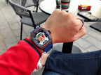 Richard Mille watch with blue strap on wrist, square dark case, skeleton dial