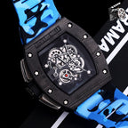 Blue camo strap watch close-up: black case, skeleton dial, visible gearwork.