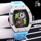 Silver-toned watch with light blue silicone strap; dark dial with green leaf art and skeleton movement.