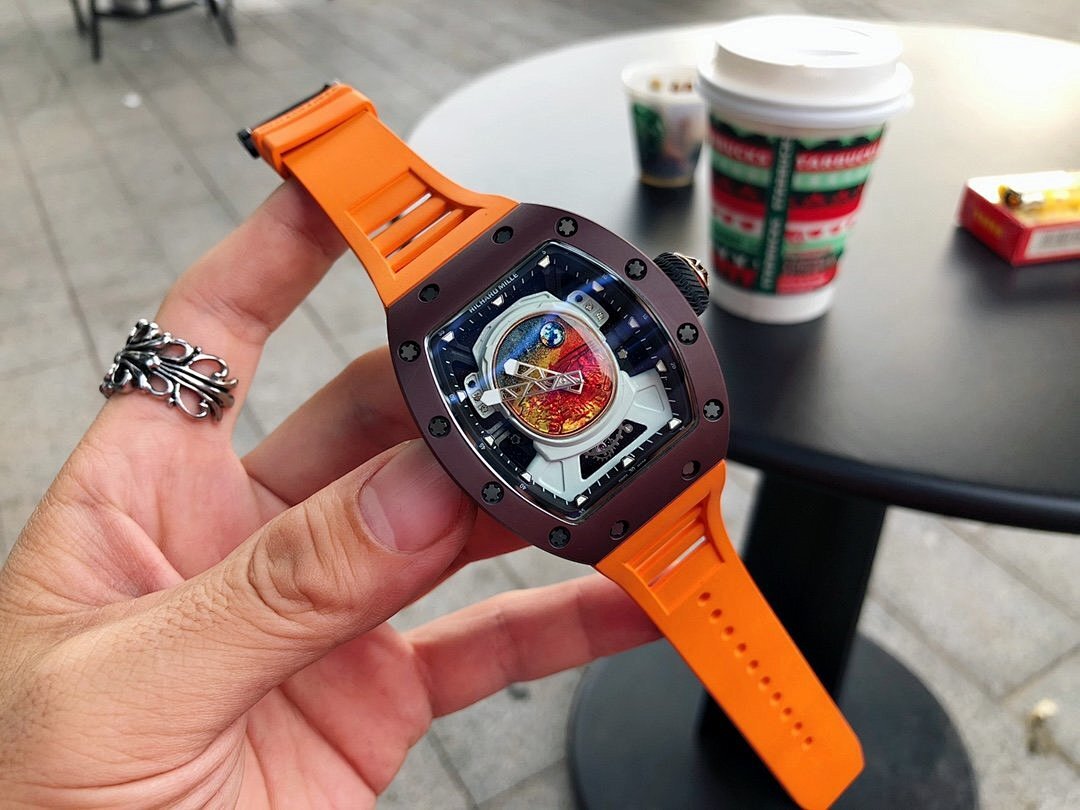 Richard Mille watch with dark brown case and orange rubber strap, colorful dial visible in hand
