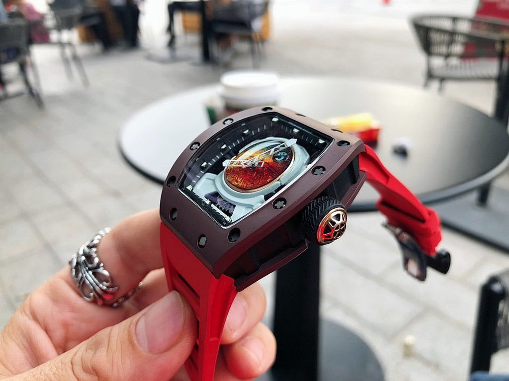 Richard Mille watch with dark brown case and red rubber strap, side angle view in hand