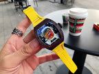 Richard Mille watch with dark brown case, yellow rubber strap, and visible colorful dial in hand