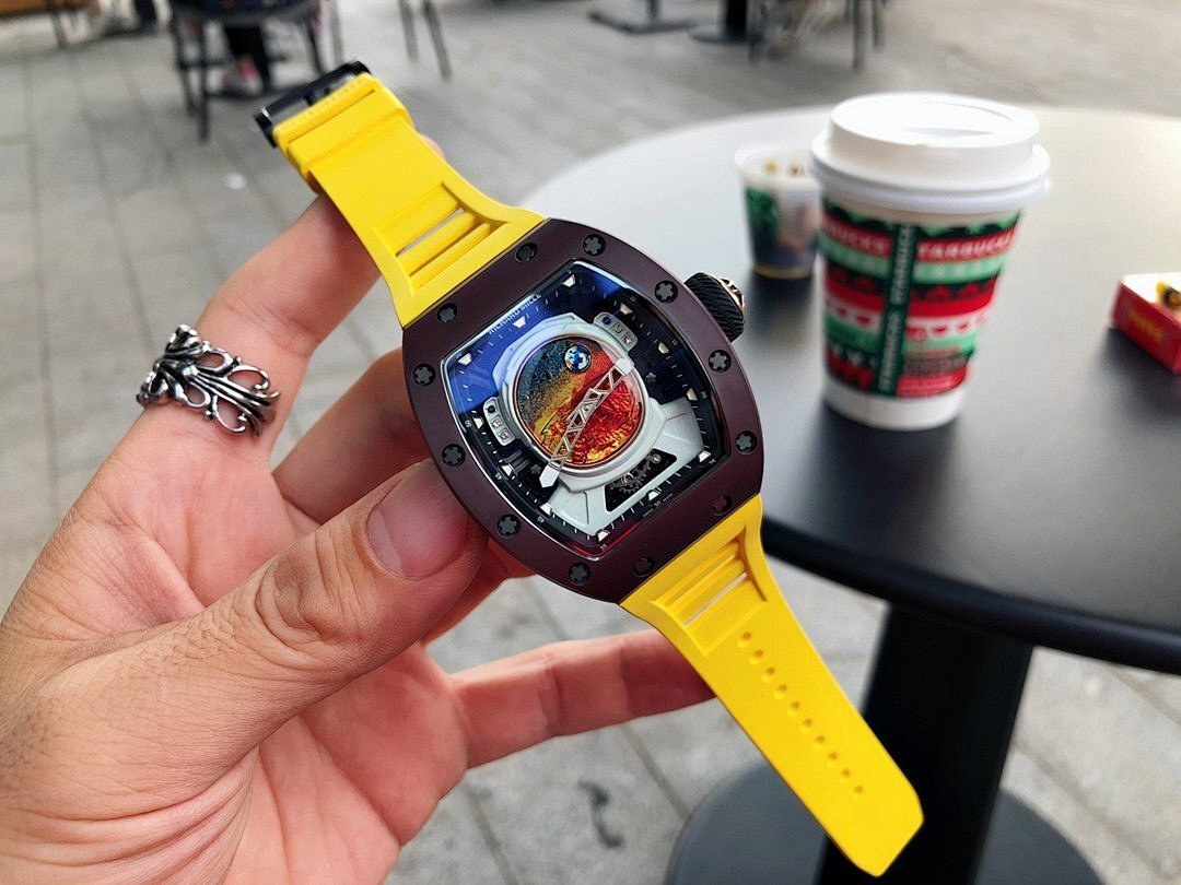 Richard Mille watch with dark brown case, yellow rubber strap, and visible colorful dial in hand
