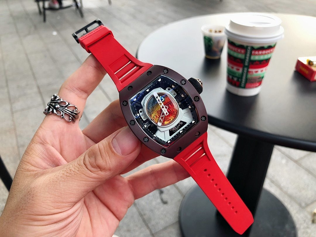 Richard Mille watch with dark brown case and red rubber strap, colorful dial visible in hand