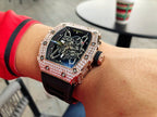 Richard Mille watch with jeweled bezel, dark skeleton dial, black strap with red accents.