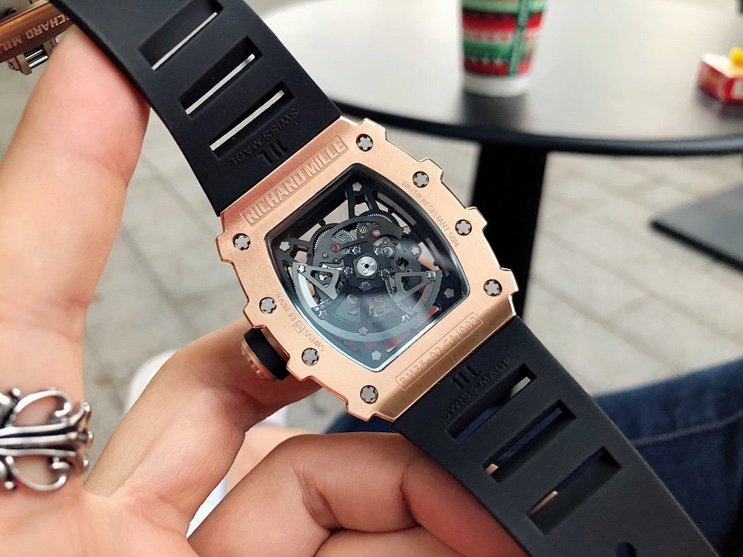 Richard Mille watch with jeweled bezel, black strap and exposed skeleton dial from side.