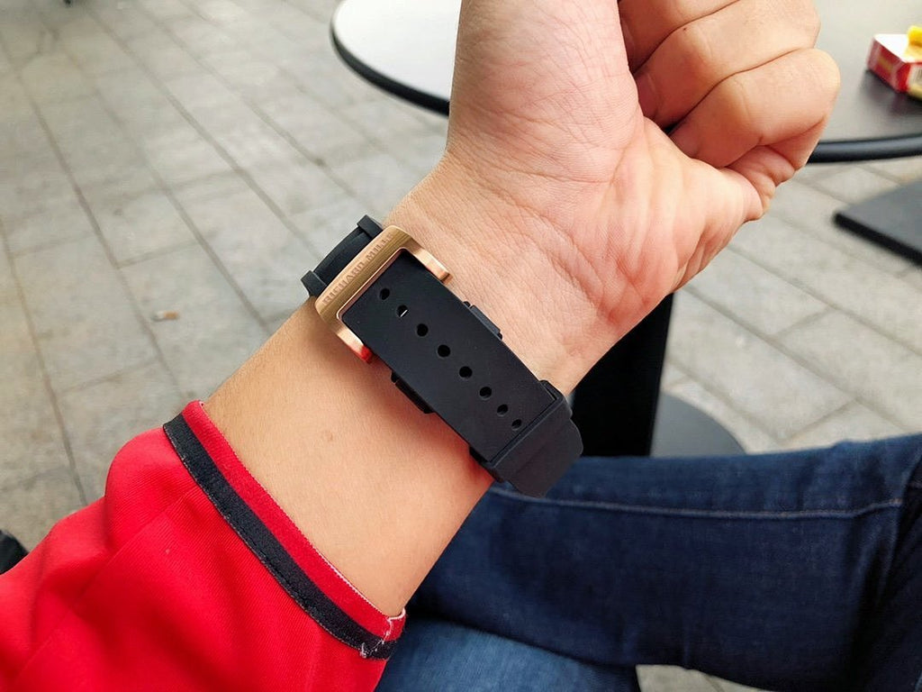 Richard Mille watch with black strap band, strap holes visible on wrist.