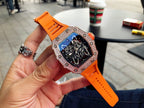 Richard Mille watch with jeweled bezel and blue skeleton dial, bright orange strap close-up.