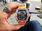 Men’s jeweled skeleton watch with bright yellow silicone strap held close-up, black dial