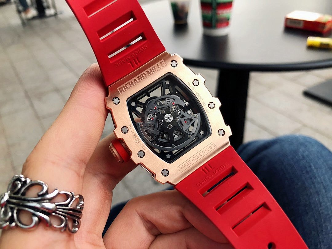 Men’s jeweled skeleton watch with red silicone strap close-up, black dial and screws