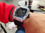 Richard Mille watch on wrist with black strap and jeweled silver case