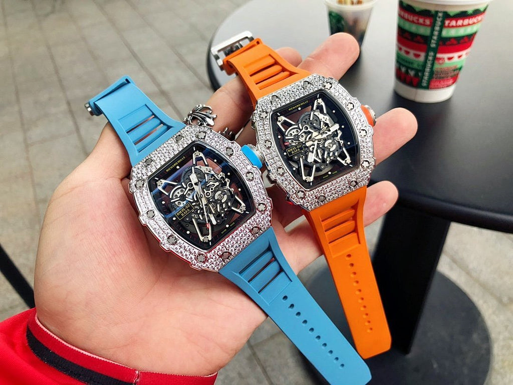 Richard Mille watches with faceted silver bezels, blue and orange rubber straps.