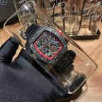 Richard Mille watch in clear display case, black strap, red bezel, skeleton dial