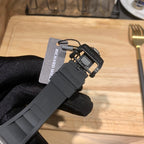 Black rubber watch strap clasp with attached tag, close-up on a hand