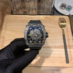 Skeleton watch with octagonal black case and blue see-through dial, held in a hand