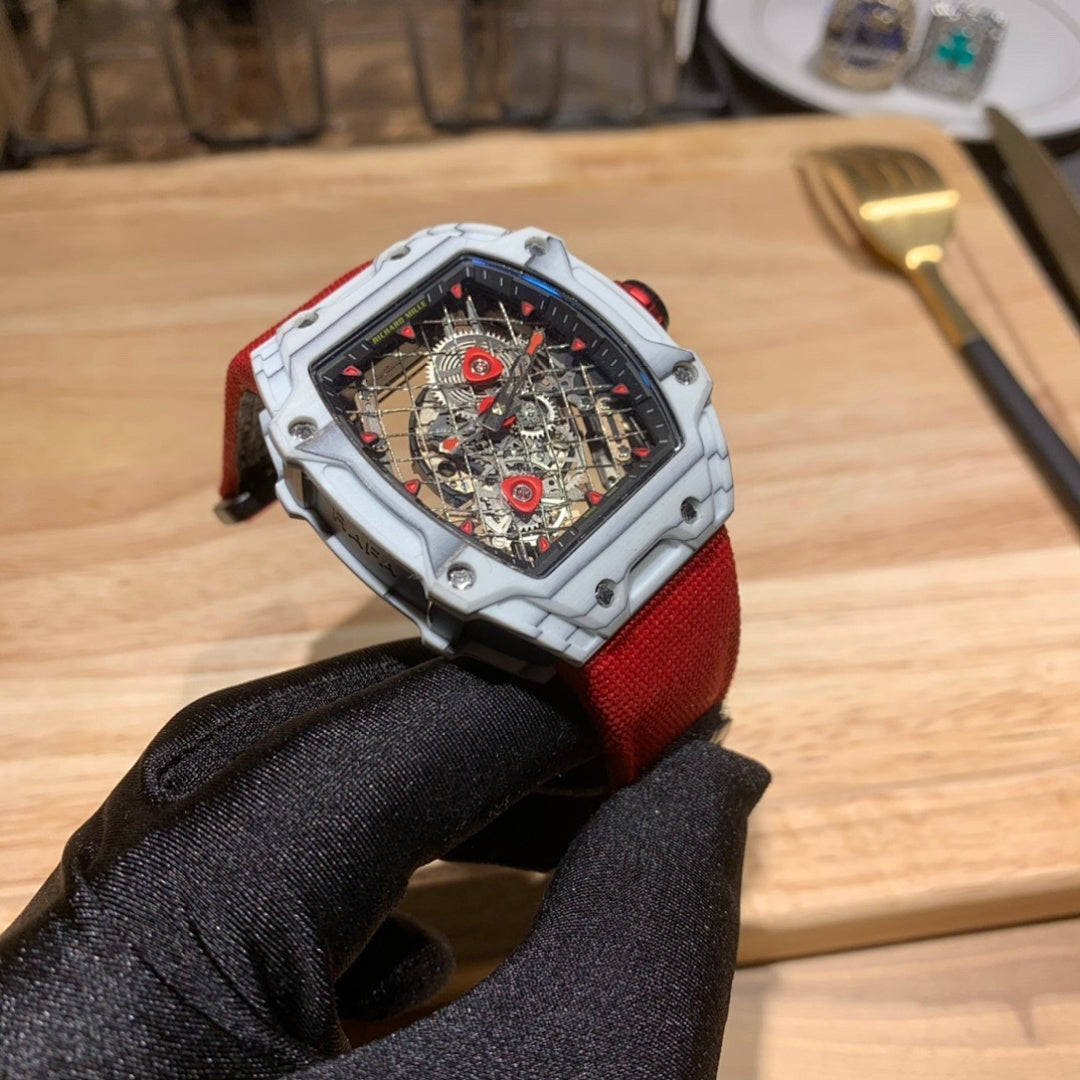 Square luxury watch with red strap and white case, skeleton dial with red accents.