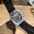 Square luxury watch with black textured strap and white case, open-work dial.