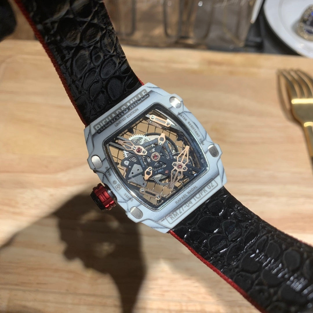 Square luxury watch with black textured strap and white case, open-work dial.