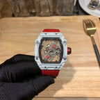 Square luxury skeleton watch with white case, red dial accents, and red rubber strap.