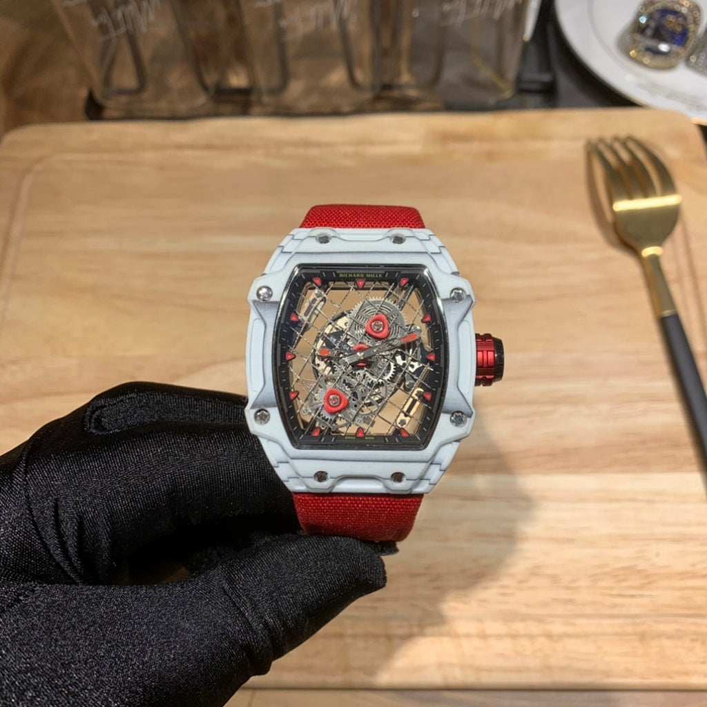 Square luxury watch with red dial accents, white case, and red rubber strap.