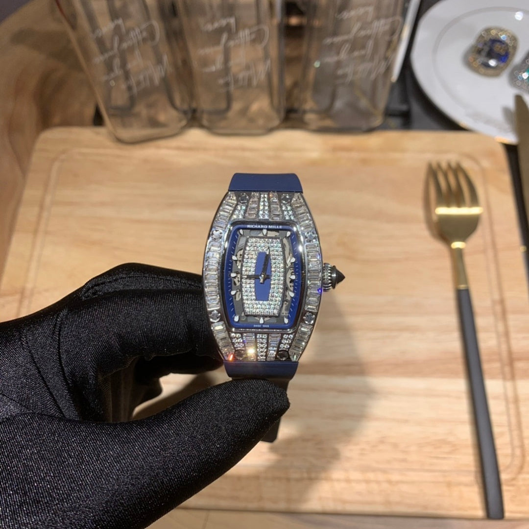 Richard Mille watch with blue strap and silver jeweled bezel, held in black glove