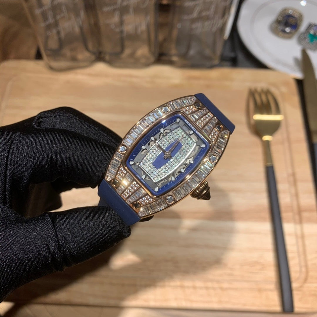 Men’s wristwatch with blue dial, jeweled bezel, and blue rubber strap, tilted close-up