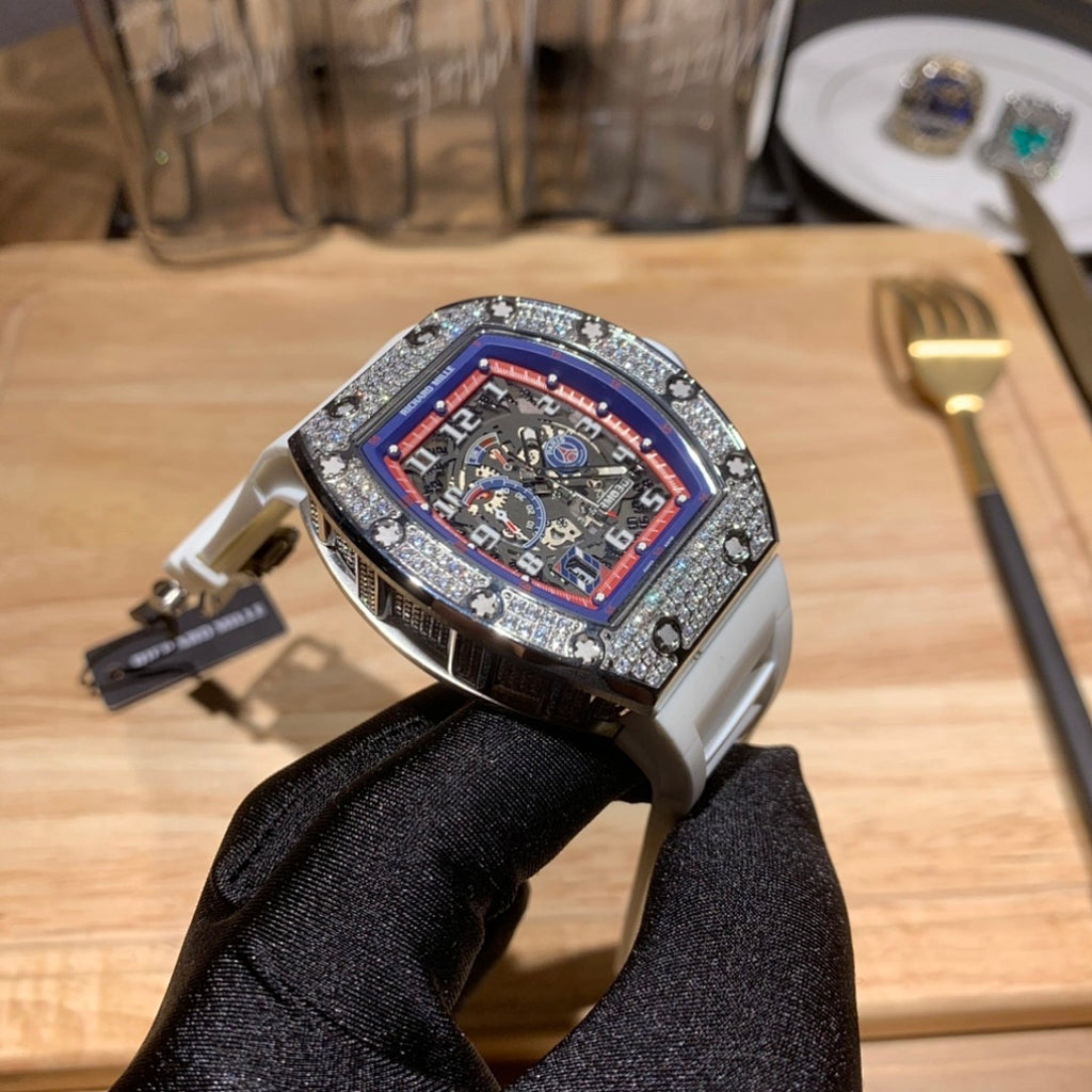 Luxury watch with white rubber strap and jeweled bezel, red-blue dial from front angle