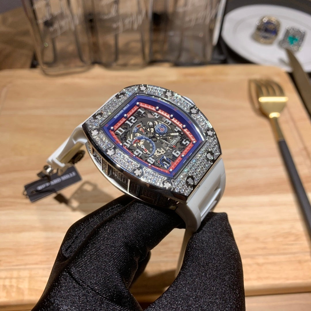 Luxury watch with white rubber strap and jeweled bezel, red-blue dial from front angle