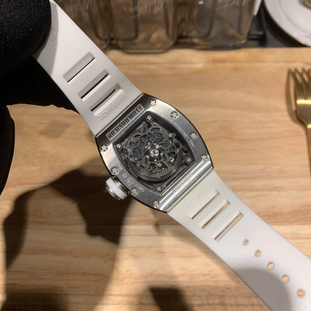 Luxury watch with white strap and steel-toned caseback, engraved skeleton interior