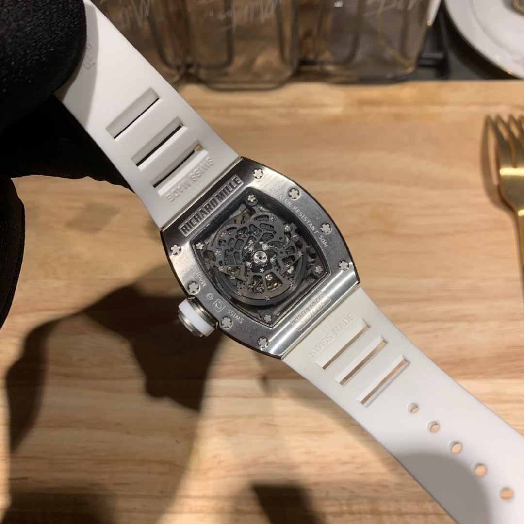 Luxury watch with white strap and steel-toned caseback, engraved skeleton interior