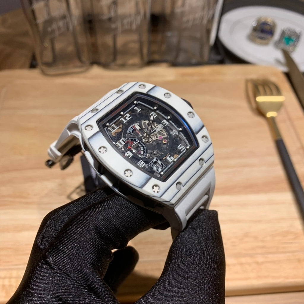 Richard Mille wristwatch side/back view, silver case and black dial on gloved hand.