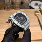 Richard Mille wristwatch side/back view, silver case and black dial on gloved hand.