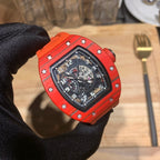 Orange watch with black dial and bezel screws, close-up held by black glove