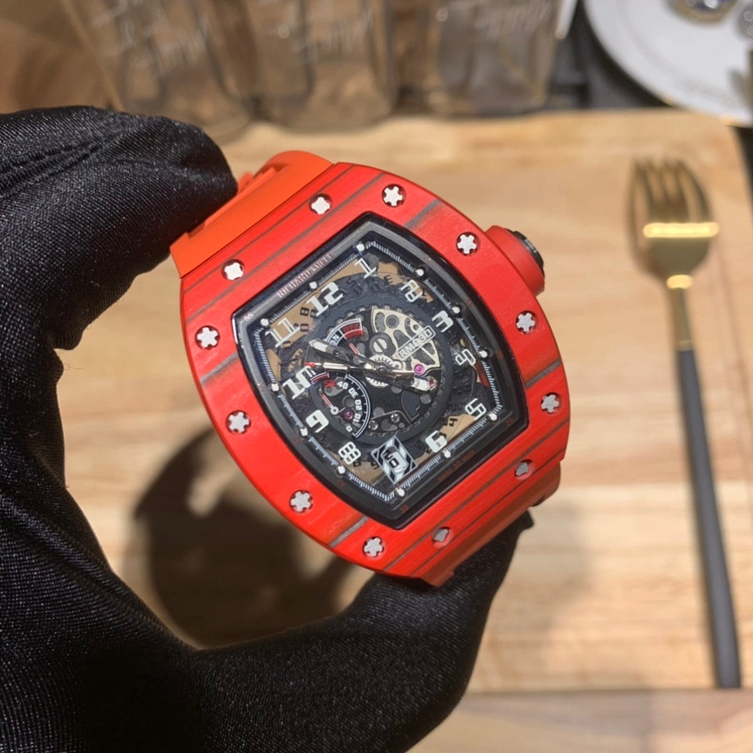 Orange watch with black dial and bezel screws, close-up held by black glove