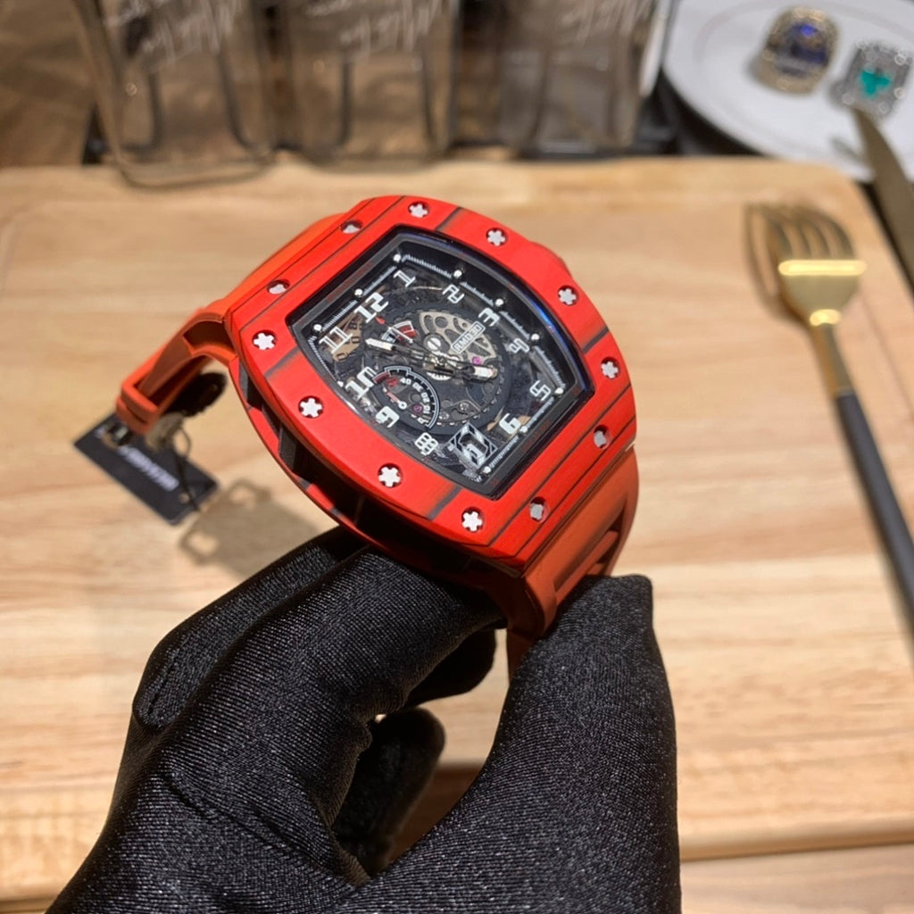 Orange watch on wrist, black dial visible, side profile held by black glove